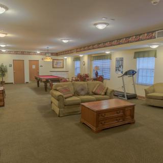 A spacious living room with a pool table, treadmill, and cozy seating area.