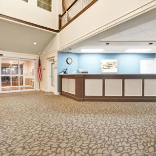 A spacious hotel lobby with a reception desk and carpeted floor.