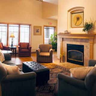 A cozy living room featuring comfortable armchairs, a fireplace, and large windows allowing natural light to fill the space.