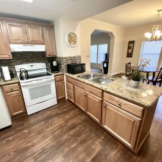 A modern kitchen with wooden cabinets, granite countertops, and stainless steel appliances.