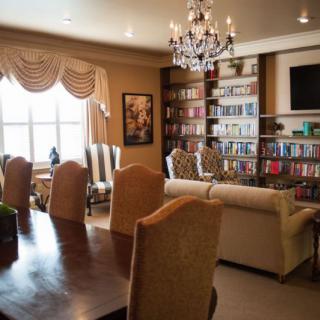 A cozy living room with bookshelves and a chandelier, featuring a dining area and comfortable seating.