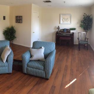 A cozy living room with two striped armchairs and a piano on a wooden floor.