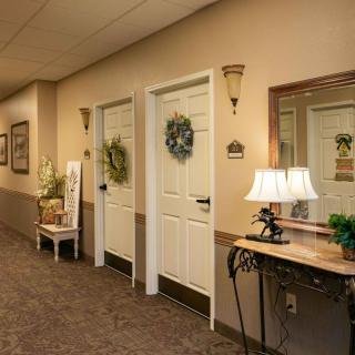 A warmly decorated hallway with doors adorned with wreaths, alongside a console table holding a lamp and mirror.