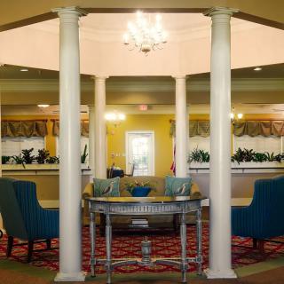 A well-decorated lobby area featuring columns, elegant furniture, and a chandelier.