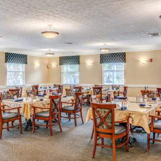 A well-lit dining room with multiple tables and chairs arranged neatly.
