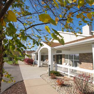 A charming house with a white porch surrounded by autumn foliage.