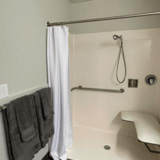Accessible bathroom with a shower featuring a grab bar and a safety seat.