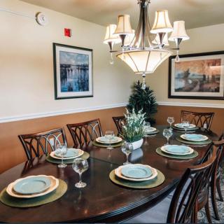 An elegantly set dining table with a chandelier and framed artwork in the background.