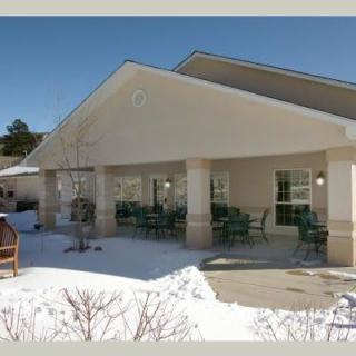 A building with a covered seating area surrounded by snow in a sunny winter setting.