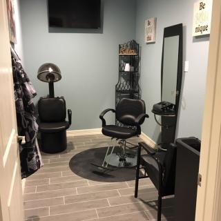 A cozy hair salon setup with a stylist chair, mirror, and hair dryer.