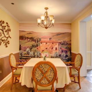 A beautifully designed dining room featuring a scenic wall mural, elegant chandelier, and a tasteful table setting.