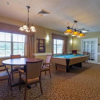 A cozy recreation room featuring a billiards table and seating area under warm lighting.