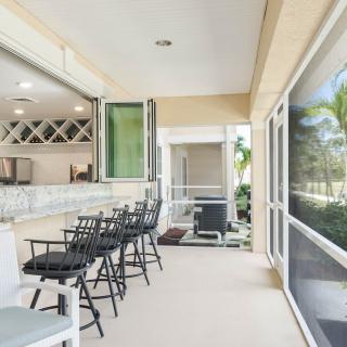 A spacious outdoor bar area with high chairs and a view of lush greenery.