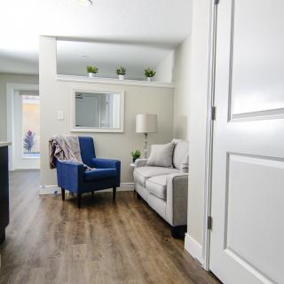 A modern living room featuring a blue chair, cozy sofa, and wood flooring with neutral decor.