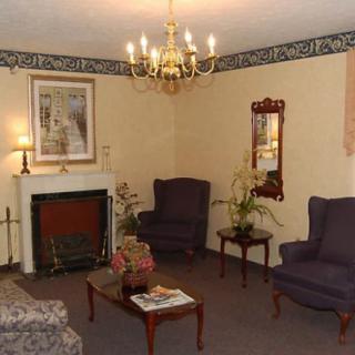 A cozy living room with a chandelier, fireplace, armchairs, and coffee table.