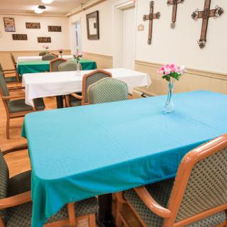 A serene dining area featuring neatly arranged tables with teal tablecloths and decorations.