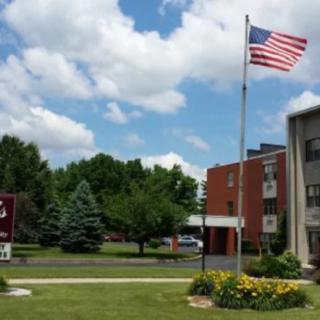 A building with an American flag and trees in the background under a partly cloudy sky.