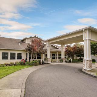 An inviting building entrance with a covered driveway surrounded by greenery.