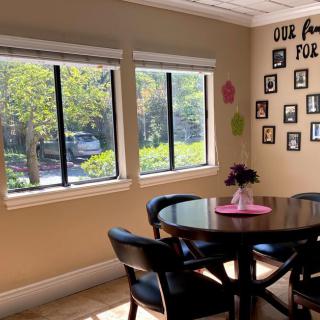A cozy dining room with a round table surrounded by chairs, adorned with family photos and bright natural light streaming through the windows.