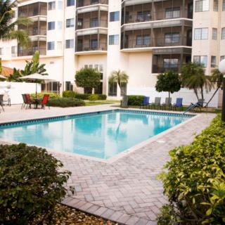 A residential apartment complex with a swimming pool surrounded by greenery.