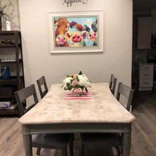 A cozy dining room featuring a rustic table with a floral centerpiece and whimsical animal artwork on the wall.