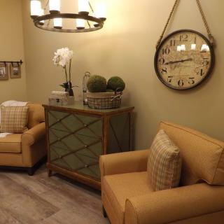 A cozy living room with warm-toned furniture, decorative plants, and a stylish clock adorning the wall.