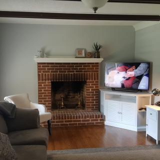 A cozy living room featuring a brick fireplace and a television next to a comfortable seating area.