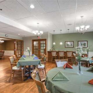 A cozy dining room with neatly arranged tables and chairs, featuring warm lighting and elegant decor.