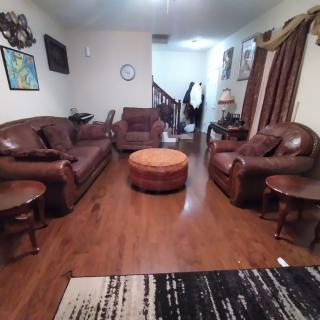 A cozy living room featuring leather couches, hardwood flooring, and warm decor.