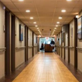 A well-lit interior hallway with wooden flooring and framed pictures on the walls.