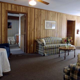 A cozy living room with wood paneling, featuring a plaid sofa and a coffee table.
