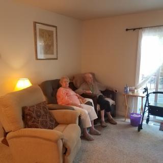 An elderly couple sitting comfortably in their living room.