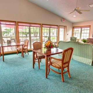 A cozy living room area with tables and chairs, featuring large windows that let in plenty of natural light.