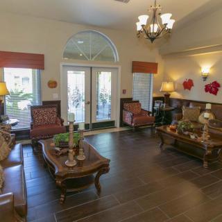 A cozy living room with elegant furniture and a chandelier, featuring large windows and warm lighting.