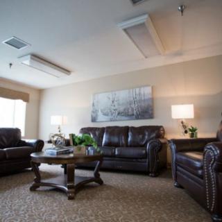 A cozy living room with leather sofas, a wooden coffee table, and soft lighting.