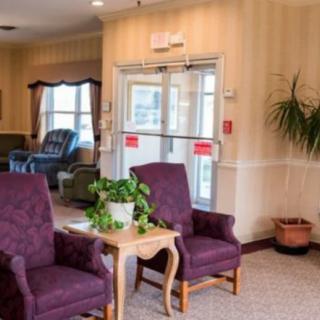 A cozy lobby area with upholstered chairs and potted plants.