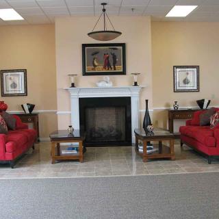 A cozy living room with red sofas and a central fireplace, complemented by decorative elements and framed art on the walls.