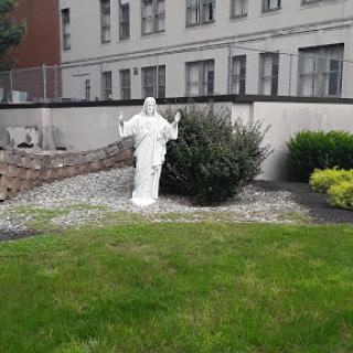 A serene white statue in a landscaped garden area.