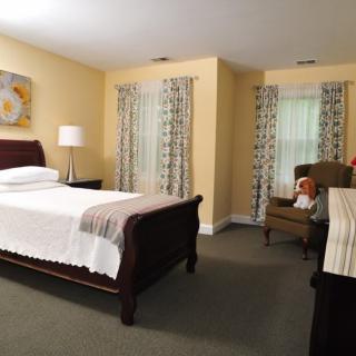 A cozy bedroom with a large bed, adorned with curtains and simple decor.