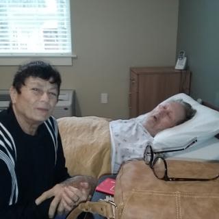 A caregiver sitting beside a patient in a hospital room, providing comfort and support.