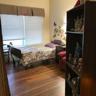 A cozy bedroom featuring a bed, shelf, and ample natural light from the window.