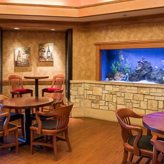 A cozy dining area in a restaurant featuring an aquarium built into the wall and wooden furniture.