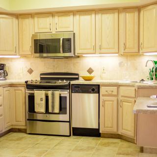 Modern kitchen with light wooden cabinets and stainless steel appliances.