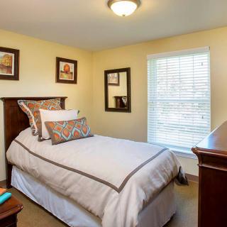 A cozy bedroom with a single bed, decorative pillows, and wall art.