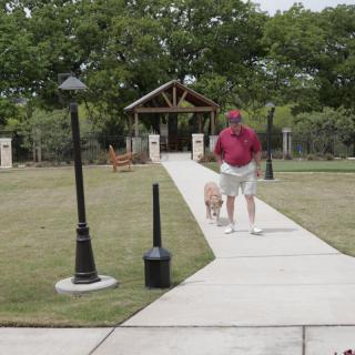 A man walking his dog along a pathway in a park.
