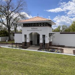 Entrance of a cemetery with a decorative arch and manicured lawn.