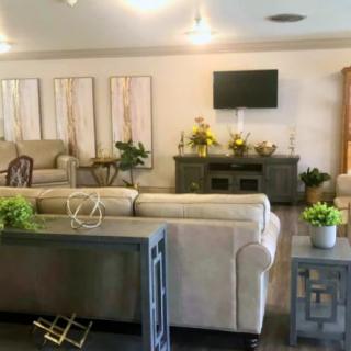 A cozy living room featuring sofas, a television, decorative plants, and stylish furniture.