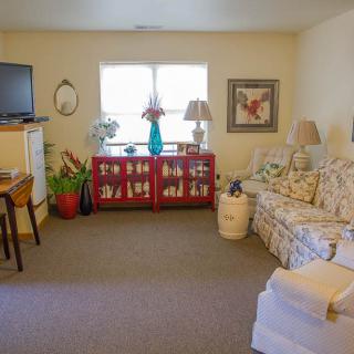 A cozy living room with a floral sofa, a television, and various decorative items.