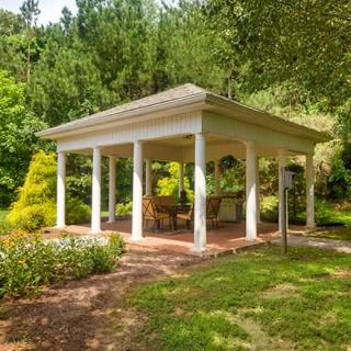 A charming gazebo surrounded by lush greenery in a tranquil garden setting.