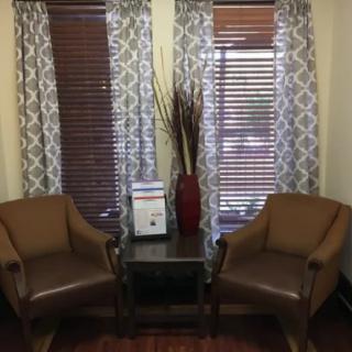 A cozy living room corner with two chairs, a small table, and decorative elements.